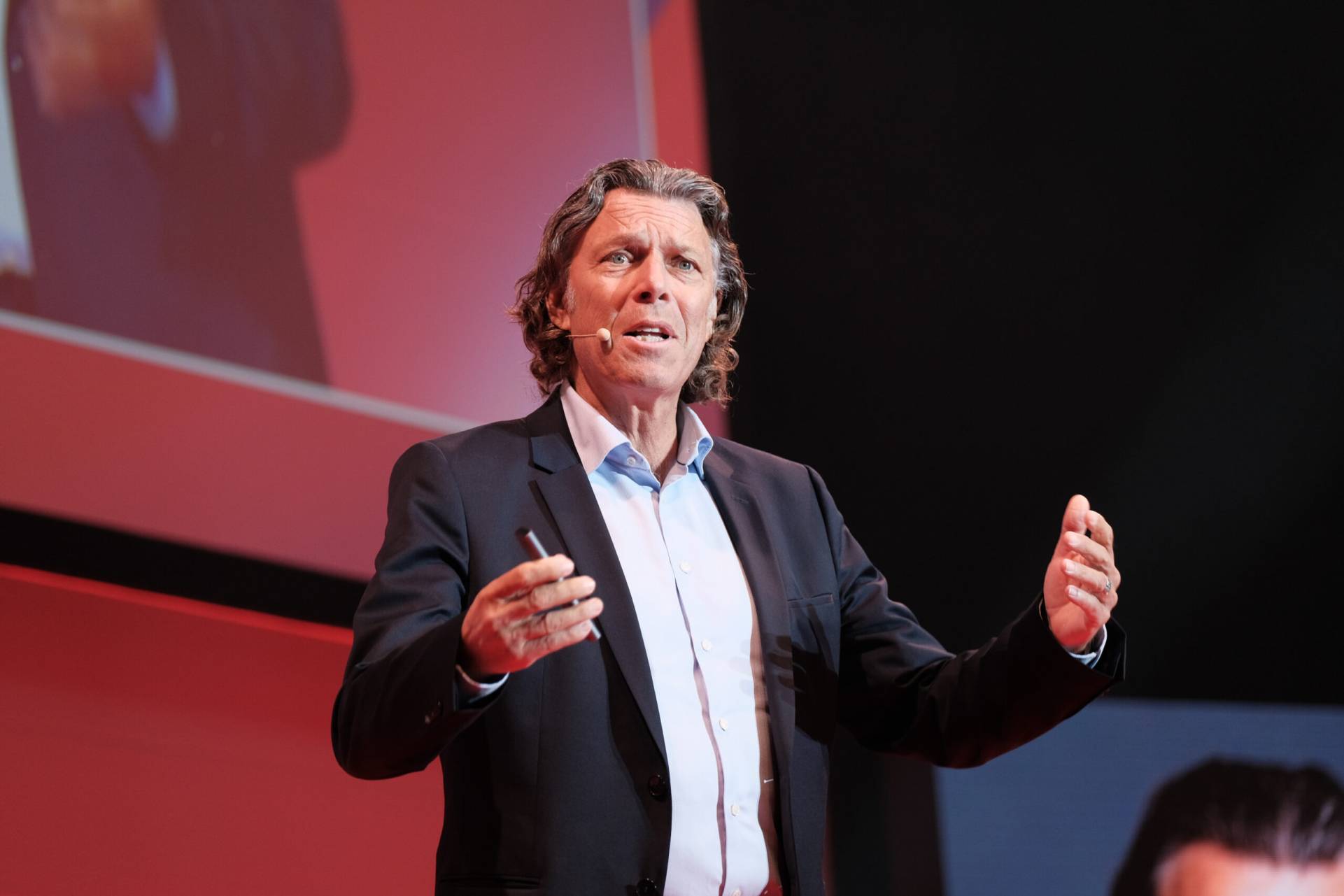 Urs Meier mit offenen Armen sprechend, Konferenzfotograf Stuttgart Leadership-Vortrag #nxtKNOWLEDGE 2025.