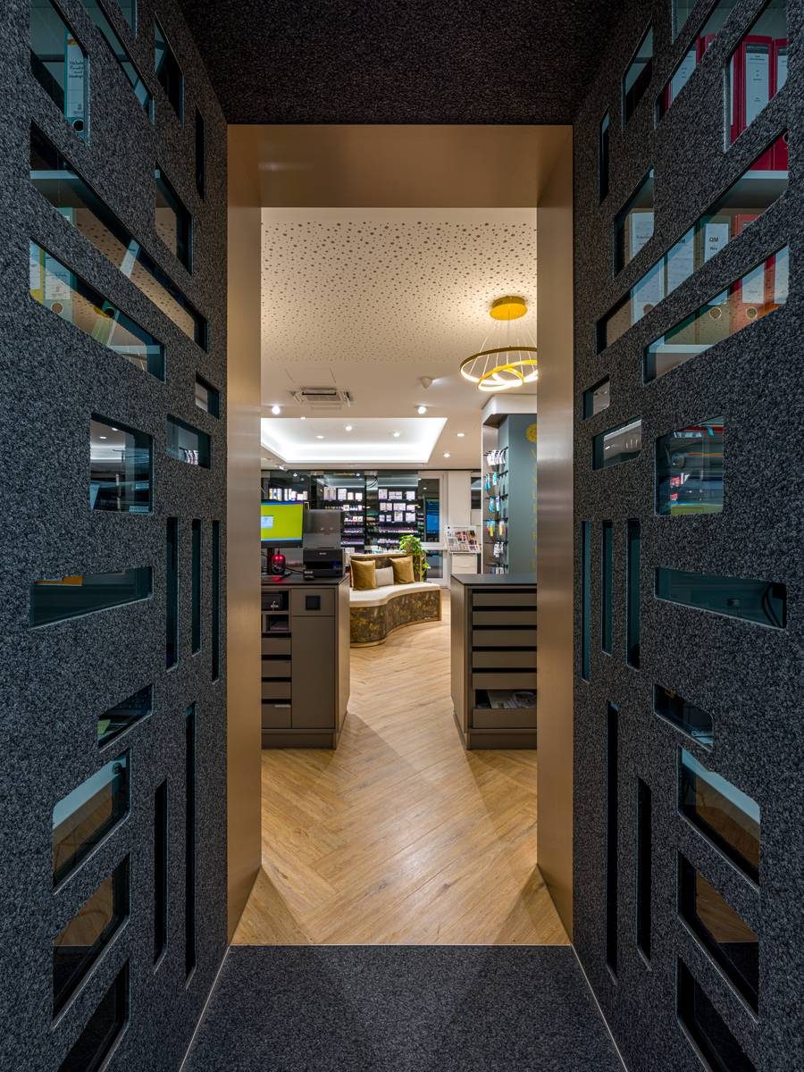 Blick durch eine Filzwand in die Offizin einer Apotheke