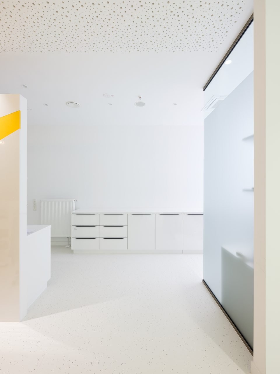 Vorbereitungsraum mit weißen Schubladenblöcken, Arbeitsfläche und einem gelben Streifen an der Wand