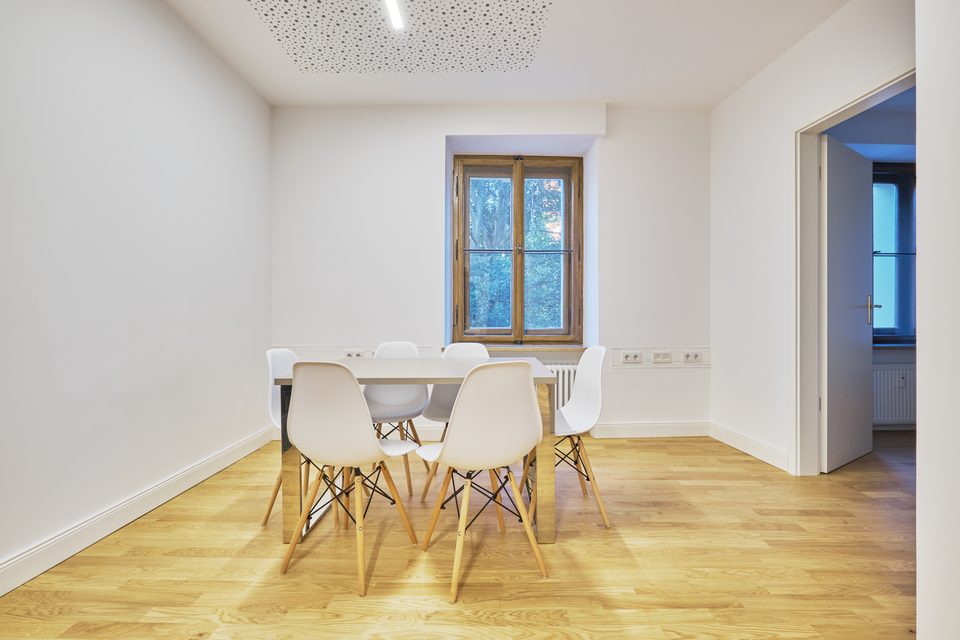 Besprechungsraum mit rundem weißem Tisch, Schalenstühlen und Blick aus dem Sprossenfenster