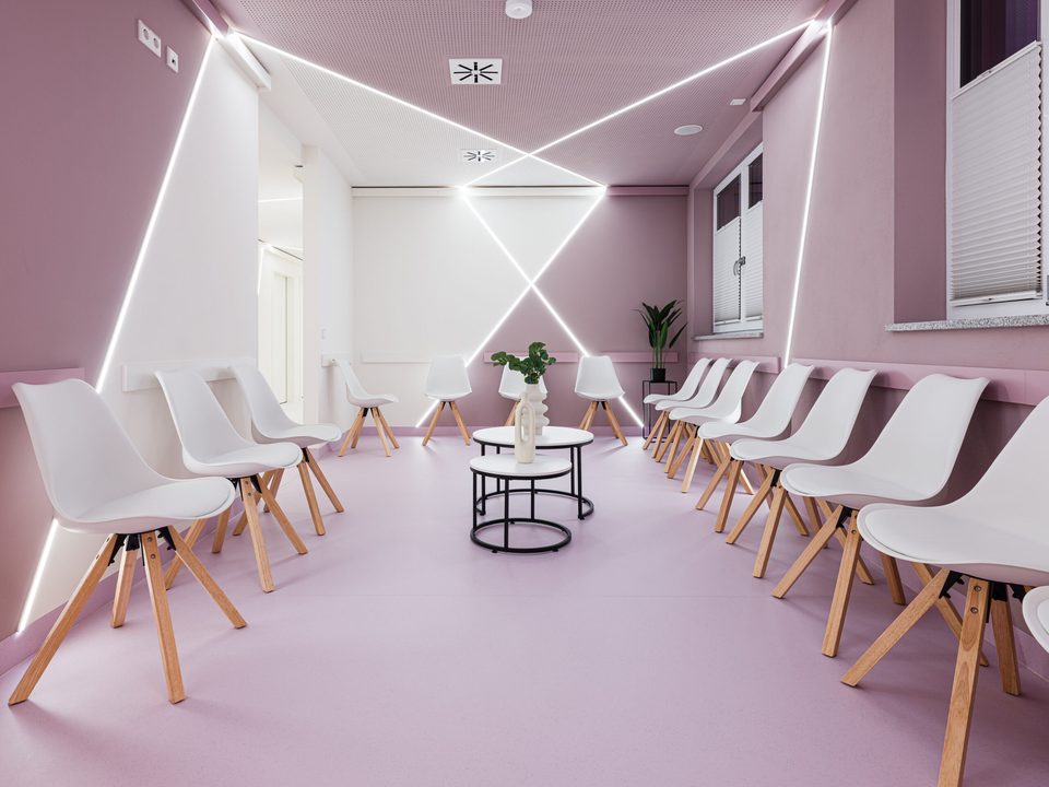 Wartebereich des Augenzentrums Cham in Rosé und Weiß mit gekreuzten LED-Lichtlinien an Decke und Wänden