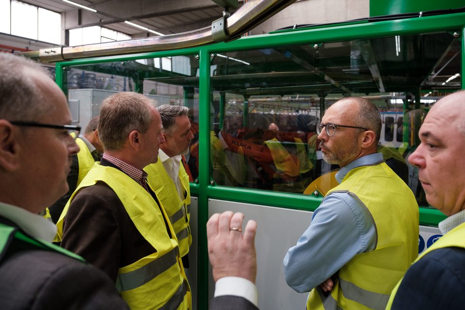 Gruppe von Gipfelteilnehmern in gelben Warnwesten lässt sich beim Werksrundgang die Anlage erklären