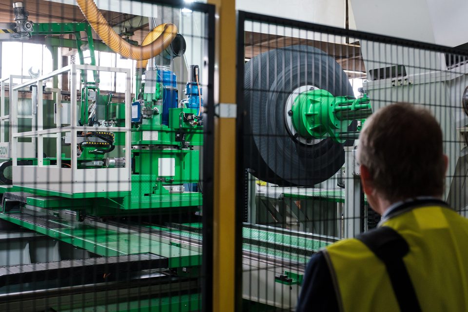 Grün lackierte Bearbeitungsmaschine hinter dem Schutzgitter, in der ein Reifen eingespannt ist