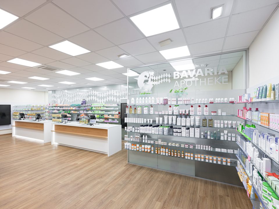 Übersicht der Offizin der Bavaria-Apotheke Bad Abbach mit Tresen und beleuchteten Produktregalen