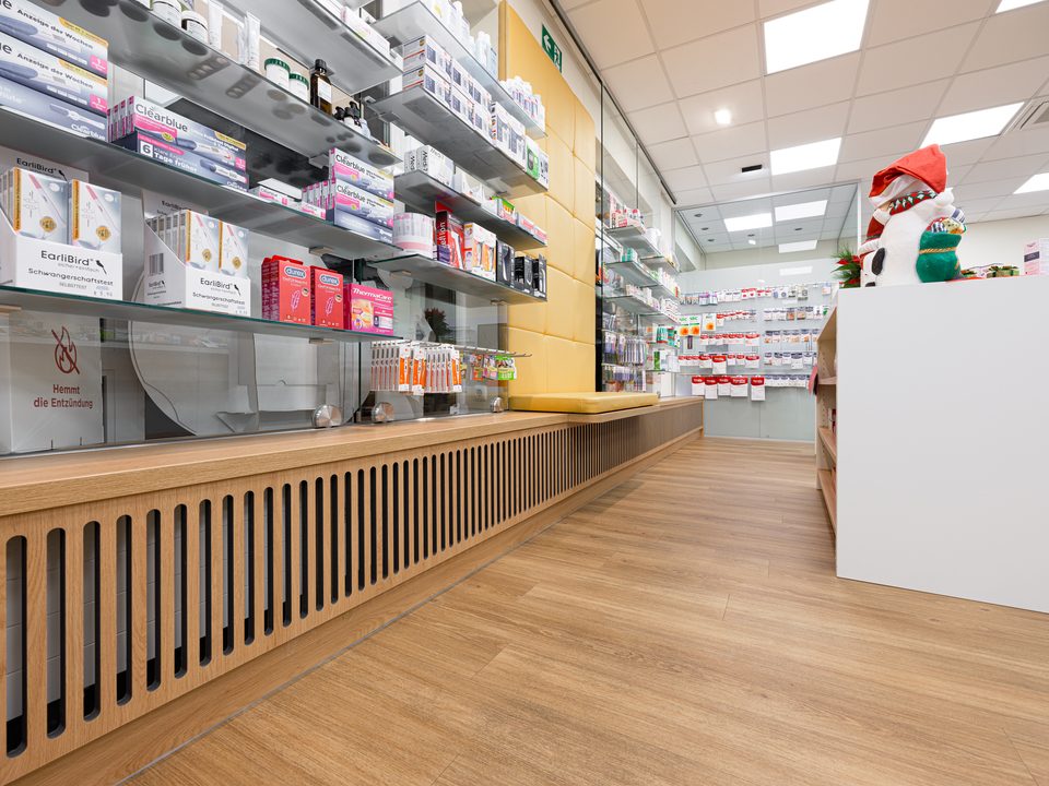 Tiefer Blick entlang der Produktregale der Bavaria-Apotheke