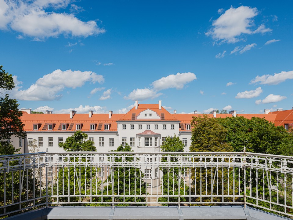 Erhöhter Blick über den Hof auf die sanierte Fassade mit Balkonbrüstung im Vordergrund
