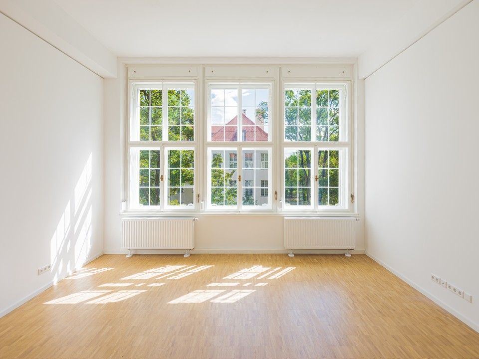 Wohnraum mit drei Sprossenfenstern, Eichenparkett und Blick auf Nachbargebäude
