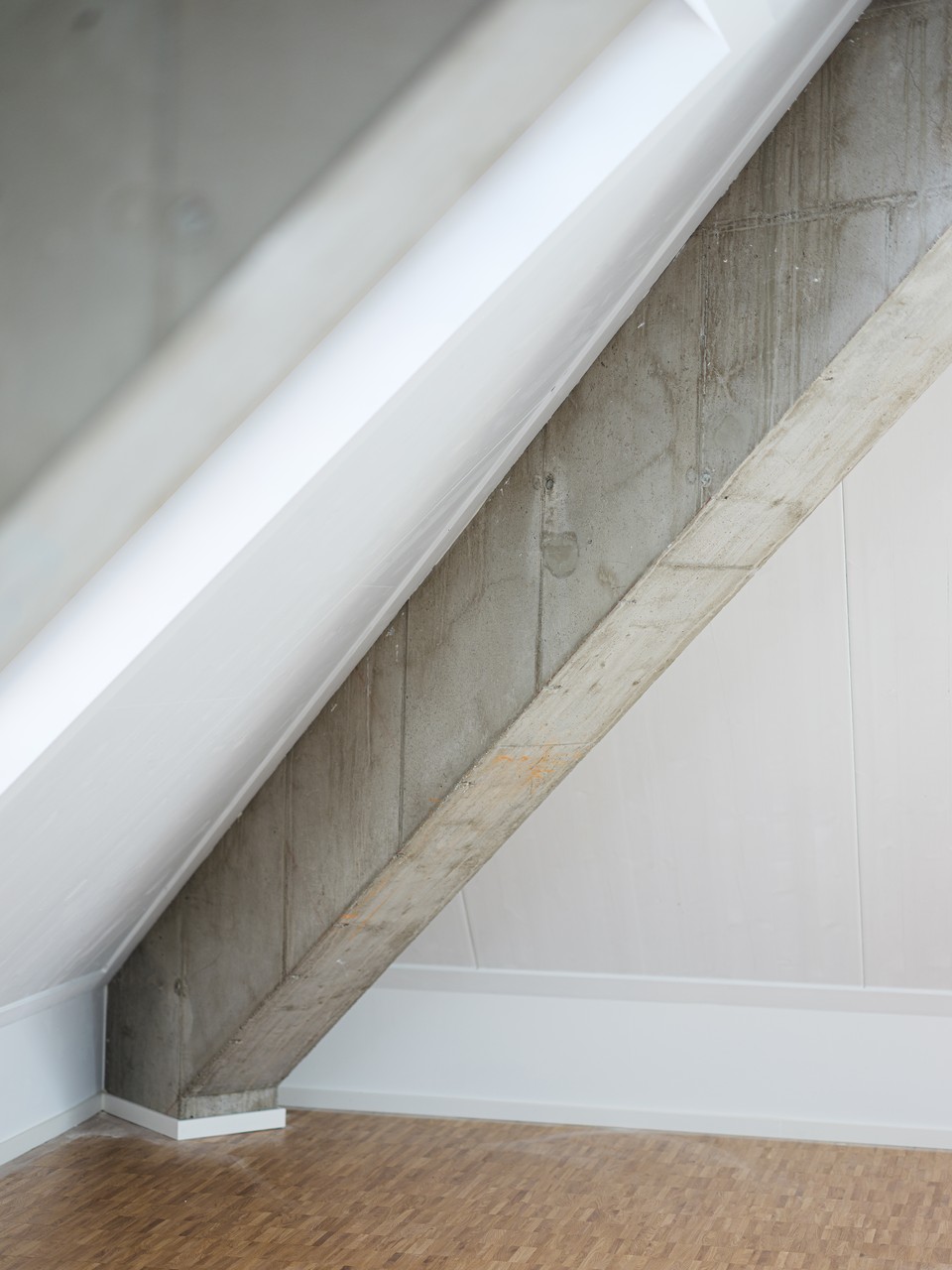 Materialdetail mit diagonaler Sichtbetonstütze auf hellem Industrieparkett
