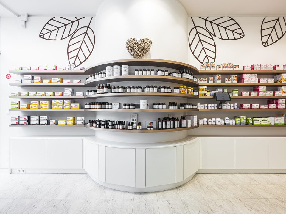 Offizin der Buchenapotheke mit geschwungener Theke und den übergroßen Buchenblatt-Zeichnungen auf der weißen Wand