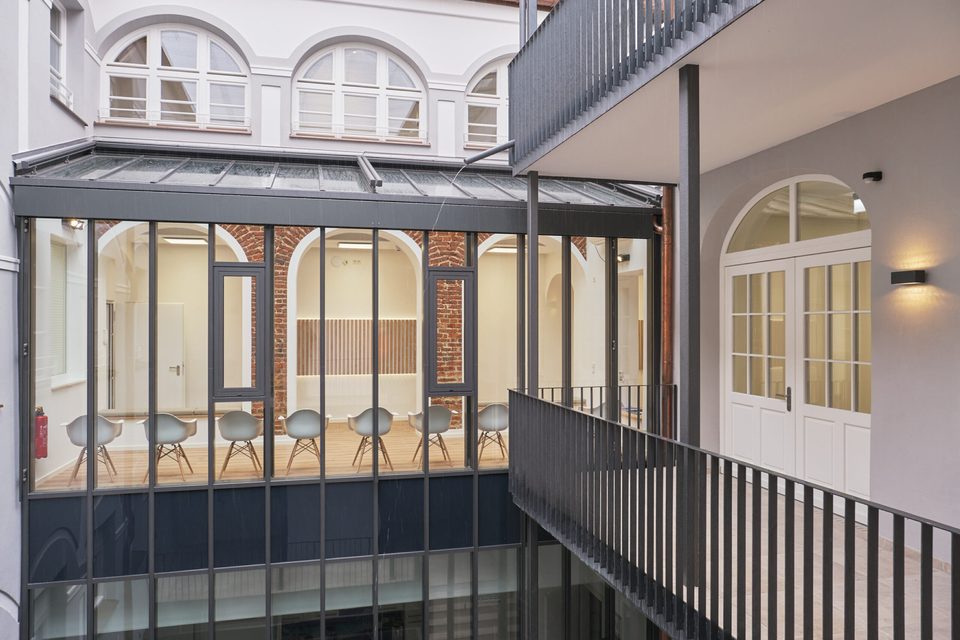 Der überdachte Innenhof des Altbaus von der Galerie aus gesehen, dahinter die Fenster der Praxis