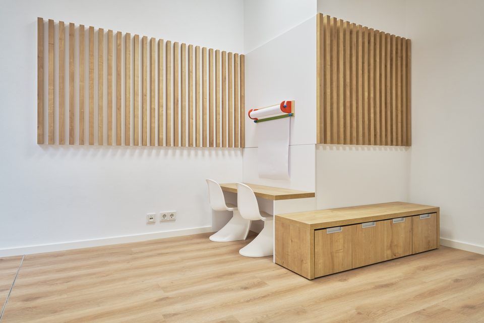 Kinderecke mit Holzlamellen-Akustikpaneelen, kleinem Stuhl und Sitzbank