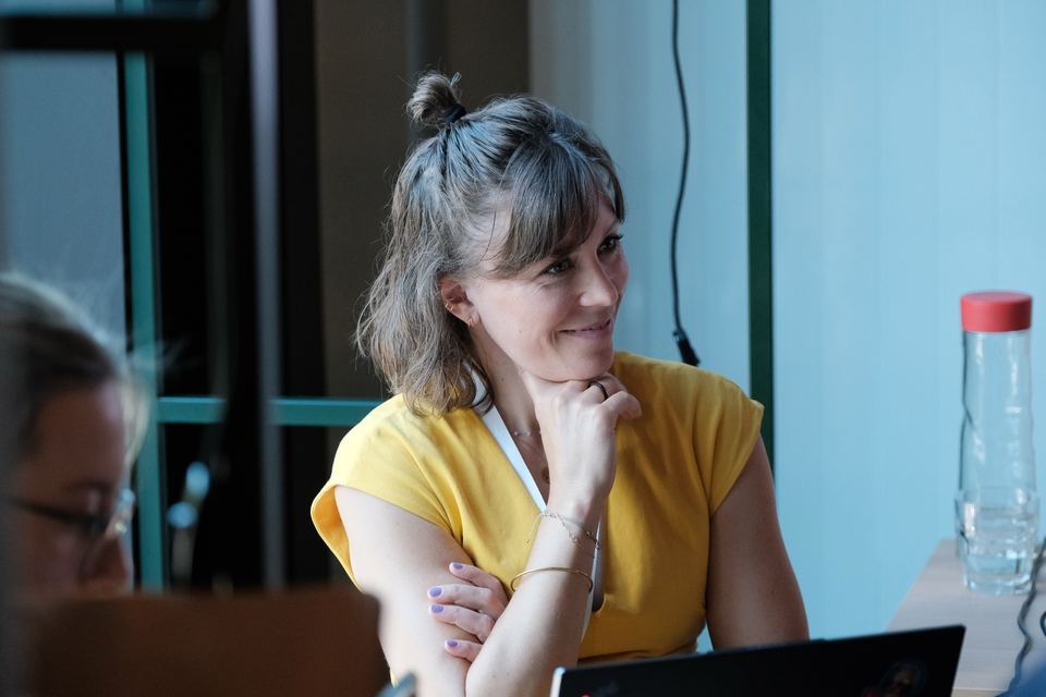 Teilnehmerin in gelbem Oberteil hört im Workshop lächelnd zu