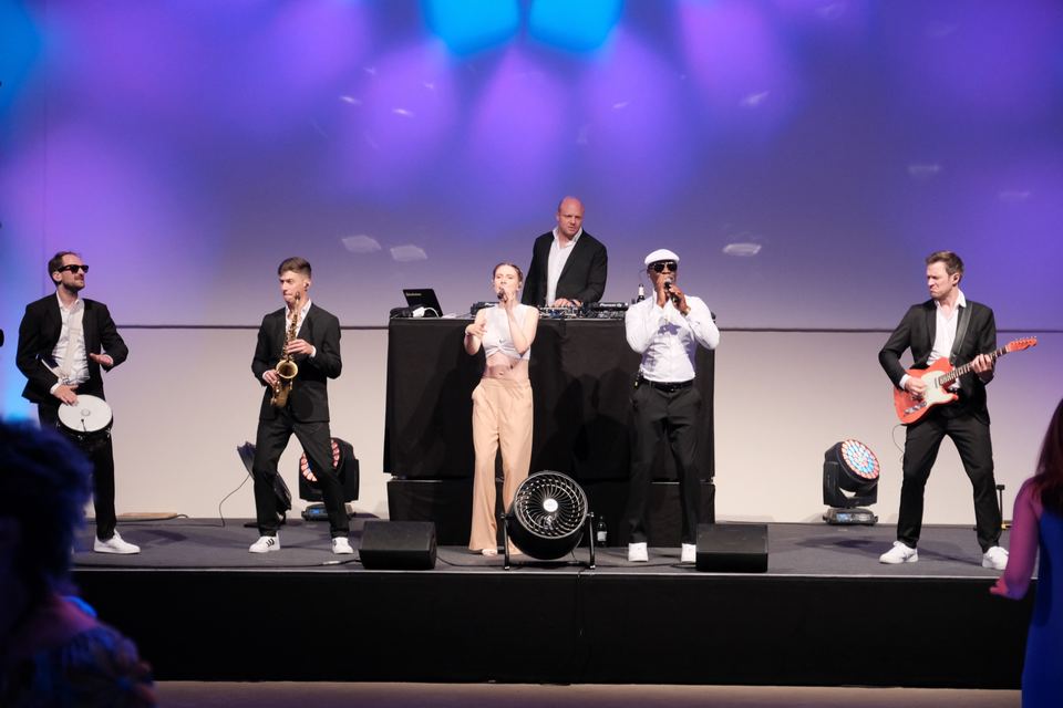 Liveband in voller Besetzung auf der bunt beleuchteten Bühne