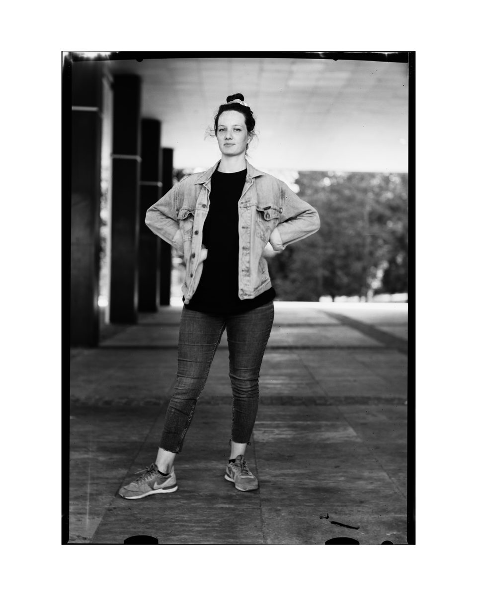 Portrait einer jungen Frau mit selbstbewusster Pose im Stadtpark Regensburg mit einer Großbildkamera auf Negativfilm