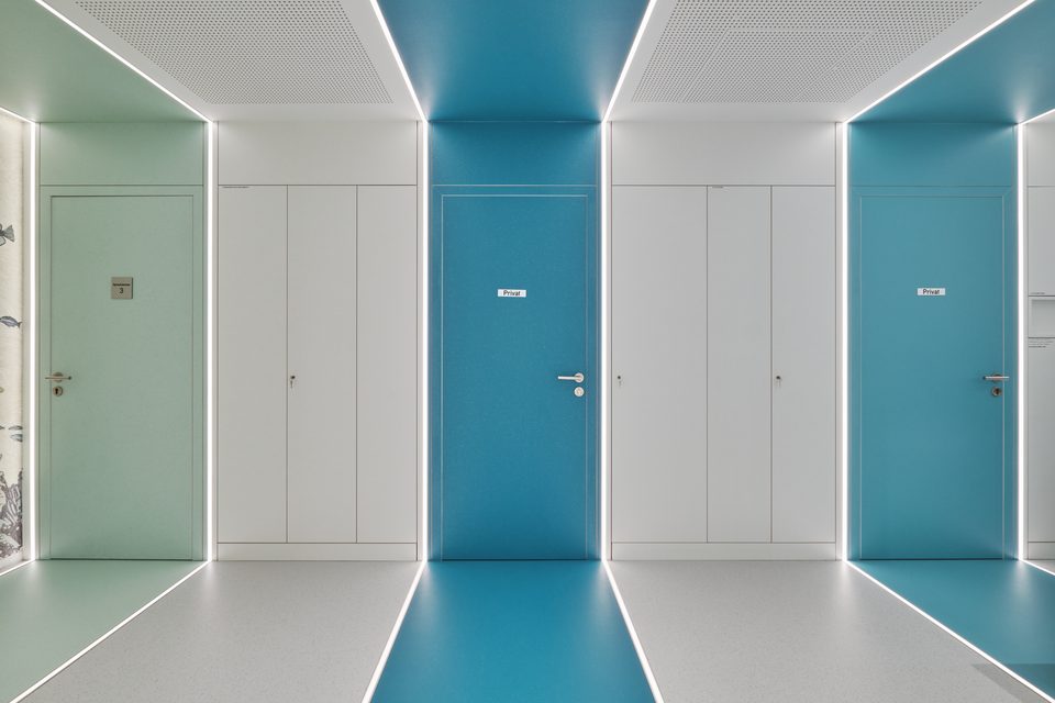 Frontale Ansicht der Türenwand, in der ein blaues Feld zwischen den weißen Türen sitzt