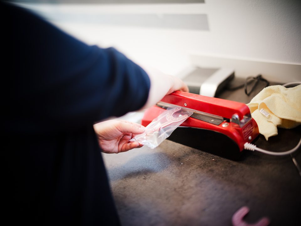 Mitarbeiterin versiegelt fertiggestellte Alignerschienen am Arbeitsplatz