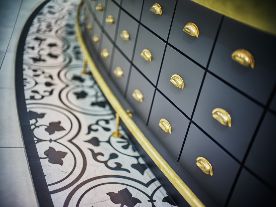 Goldene Muschelgriffe an der navyfarbenen Schubladenwand der Löffl’schen Apotheke