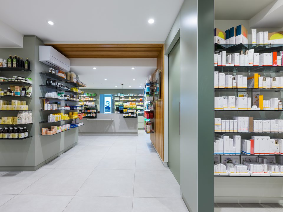 Verkaufsregale der Marienapotheke Schongau mit Pflegeprodukten zwischen salbeigrünen Pfeilern