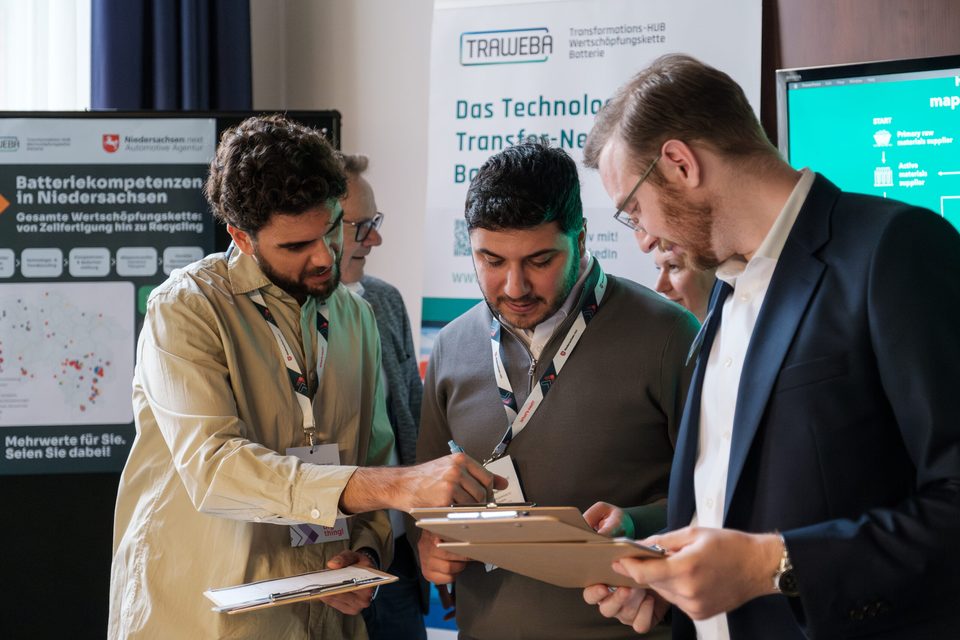 Drei Besucher notieren am Messestand „Batteriekompetenzen in Niedersachsen" auf Klemmbrettern.