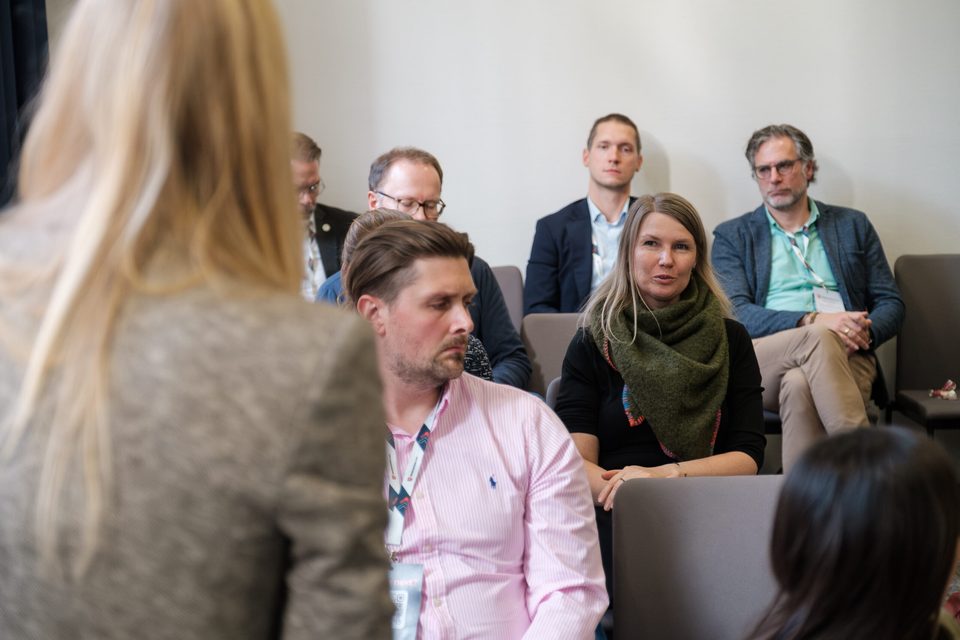 Podiumsrunde in Sesseln, die Teilnehmenden hören einer Frage aus dem Publikum zu.