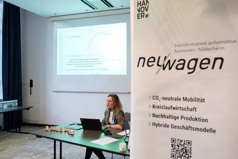 Workshop des Netzwerks neu/wagen, daneben ein Rollup zu CO₂-neutraler Mobilität und Kreislaufwirtschaft.