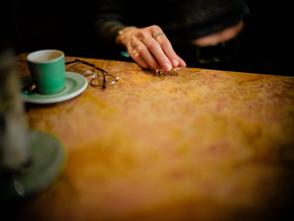 Detailaufnahme einer Hand mit Tasse auf rustikalem Tisch im Orphée