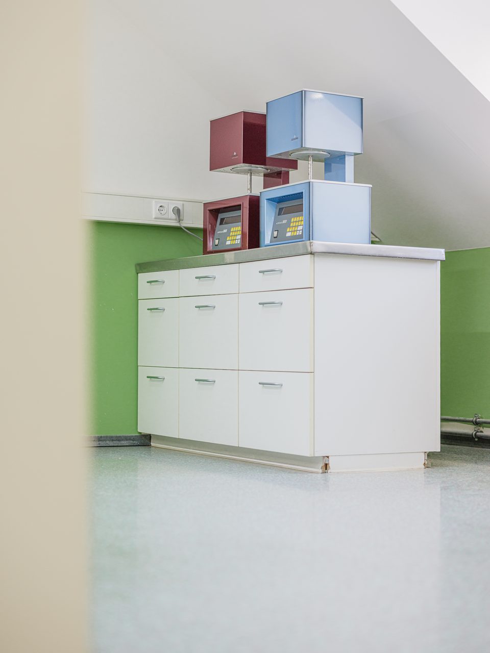 Hohe weiße Laborschränke vor der zweigeteilten Wand in Weiß und Apfelgrün