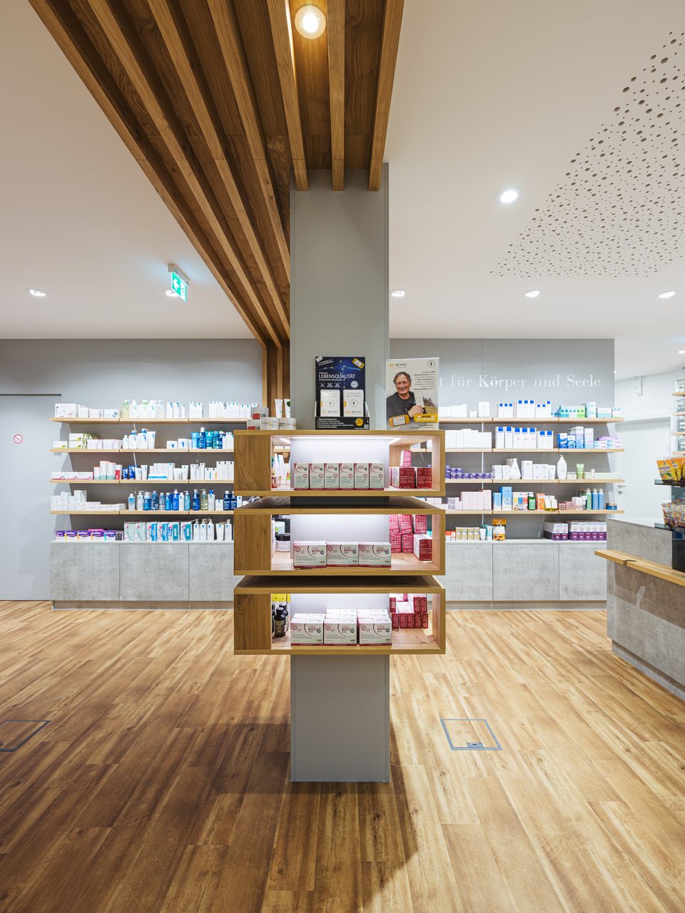 Säule mit Produktregalen in Holzdesign der Salven-Apotheke