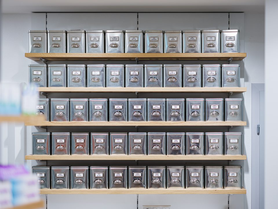 Regal mit Blechdosen für lose Kräuter in der Salven-Apotheke