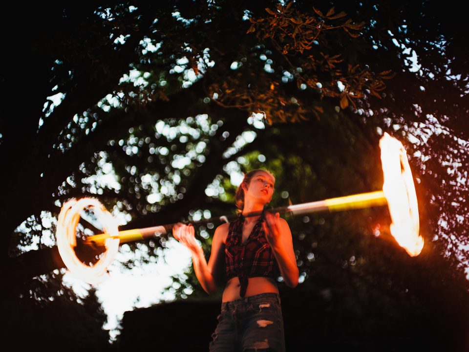 Portrait beim Feuerjuggling im Feuerschein, Burgruine im Hintergrund