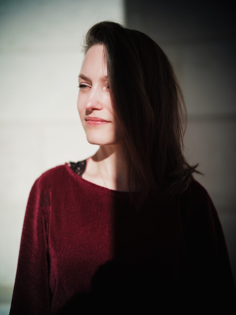 Portrait einer jungen Frau in modischem, roten Overall auf der Walhalla bei Regensburg, das Gesicht zur Hälfte im Sonnenlicht