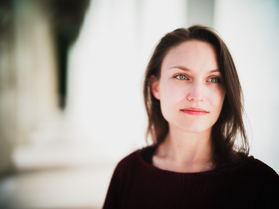 Portrait einer jungen Frau, Blick aus dem Bild heraus, in der Hintergrundunschärfe die Walhalla bei Regensburg