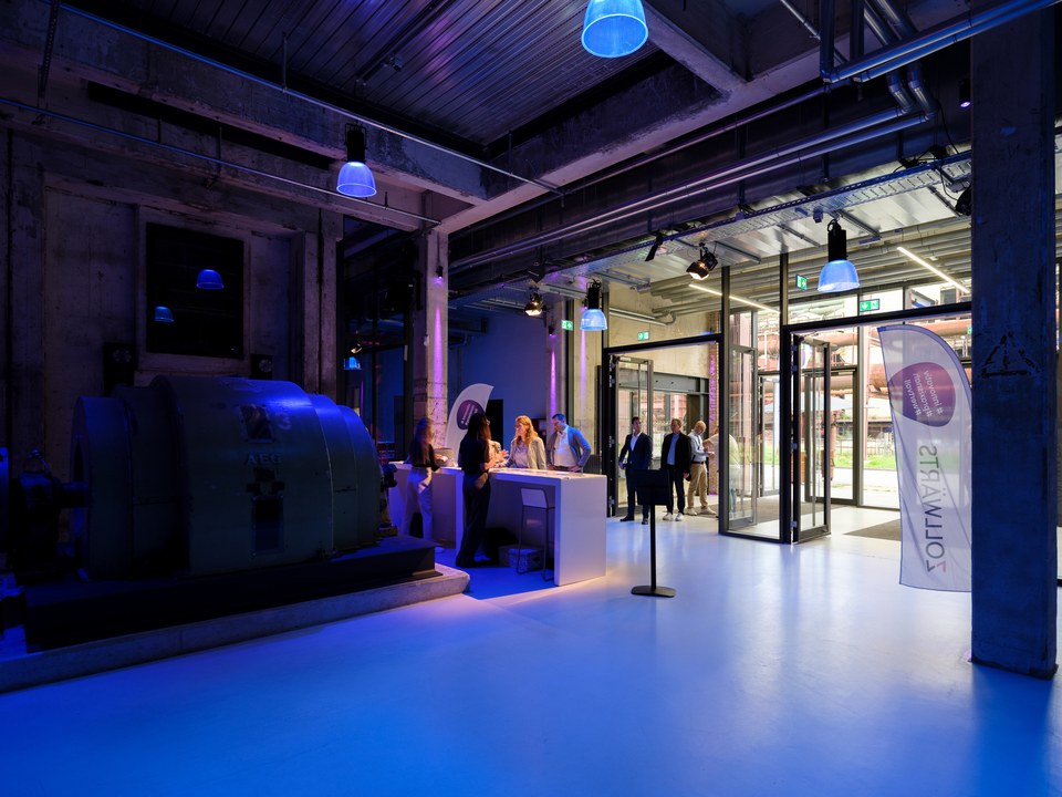 Foyer mit blau beleuchtetem Boden, historischen Maschinen und der Registrierung vor der Glasfront