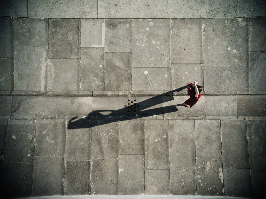 Junge Frau in modischem, rotem Overall auf der Walhalla bei Regensburg von oben mit Schattenwurf