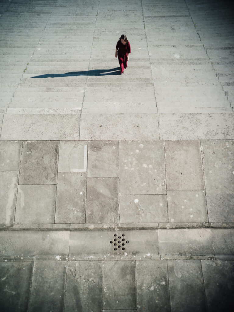 Junge Frau in modischem, rotem Overall auf den Stufen der Walhalla bei Regensburg