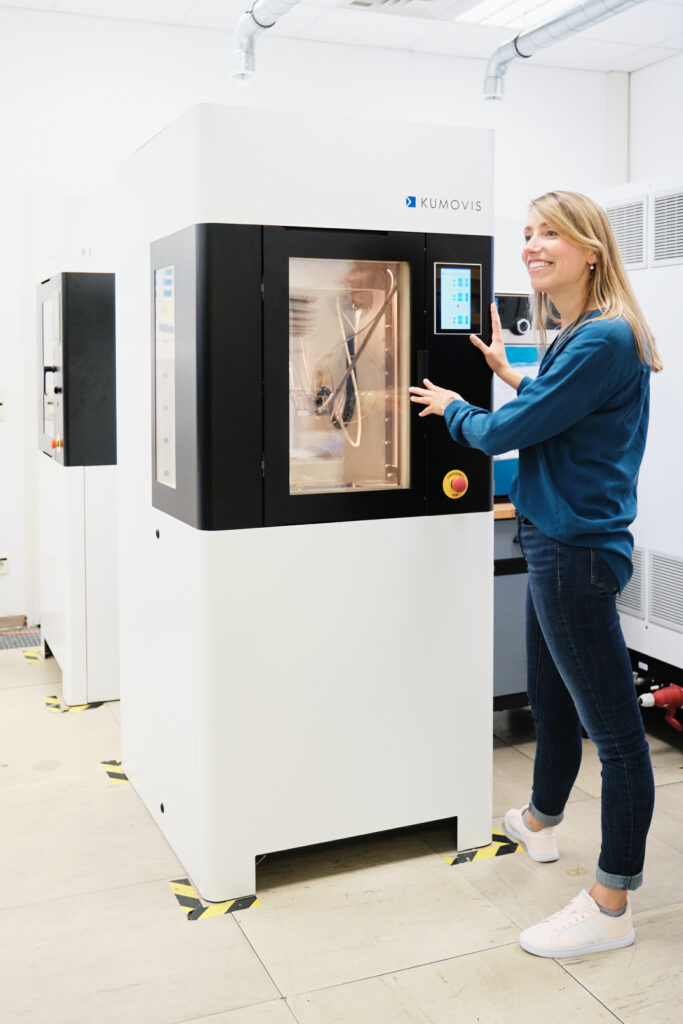 Gründerin einer High-Tech-Firma lächelnd am Bedienfeld eines High-End-3D-Druckers, Editorial für KontakTUM