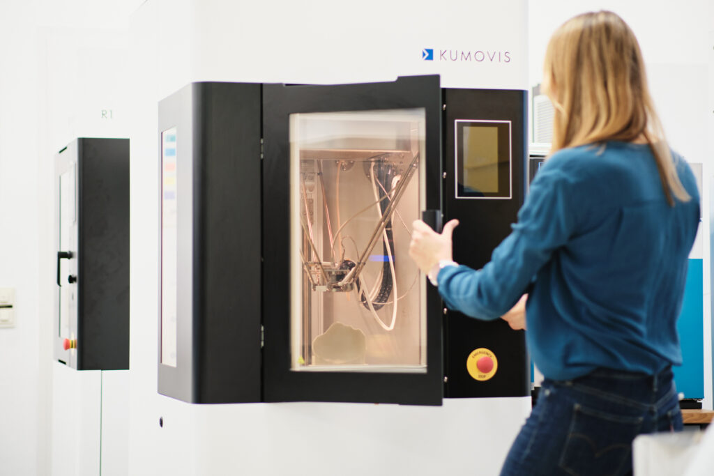 Gründerin einer High-Tech-Firma entnimmt Bauteil aus einem High-End-3D-Drucker, Editorial für KontakTUM