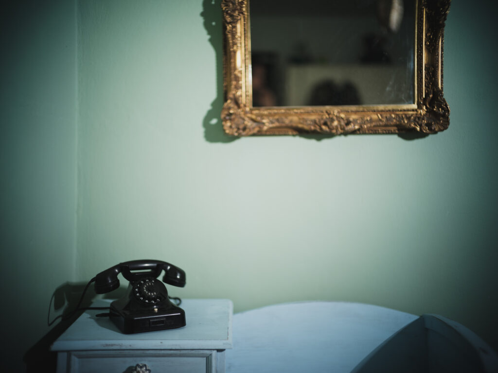 Altes Telefon und Spiegel mit Barockrahmen an der Wand in einer Regensburger Wohnung