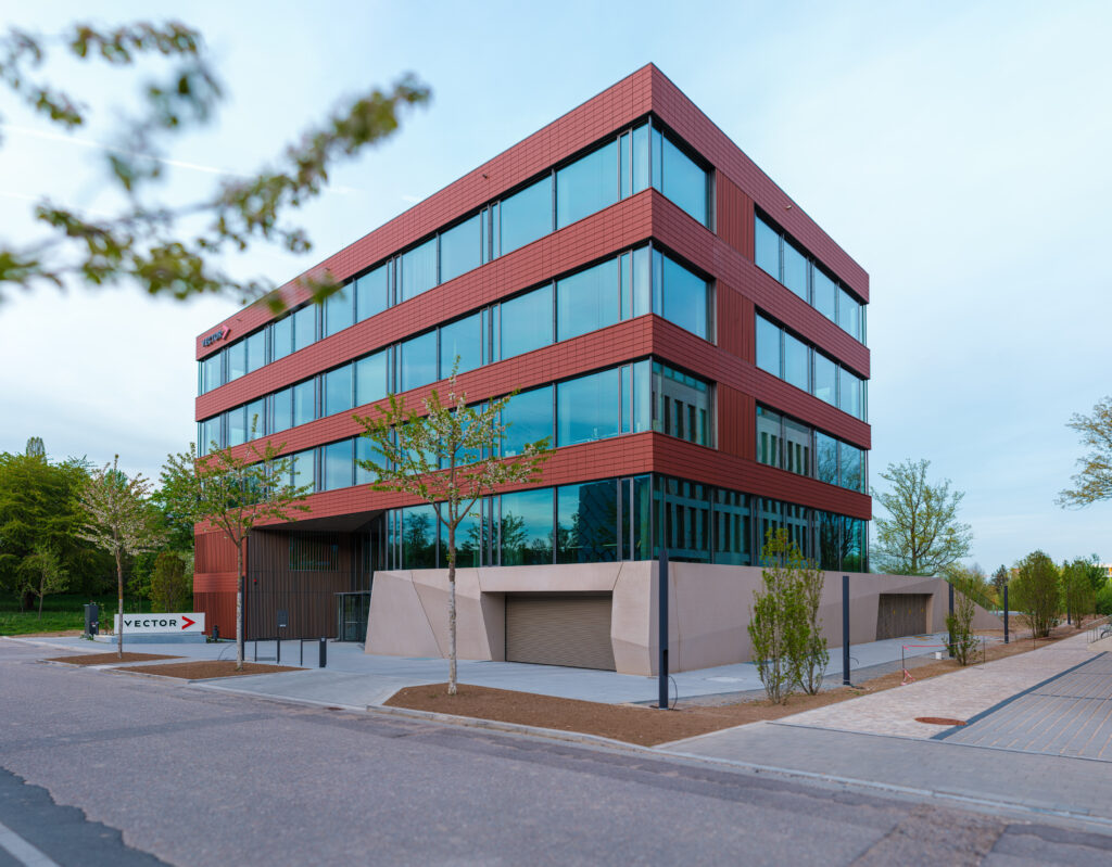 Gesamtansicht des neuen Vector-Bürogebäudes in der TechBase Regensburg mit Schärfeverlauf und Frühlingsbäumen