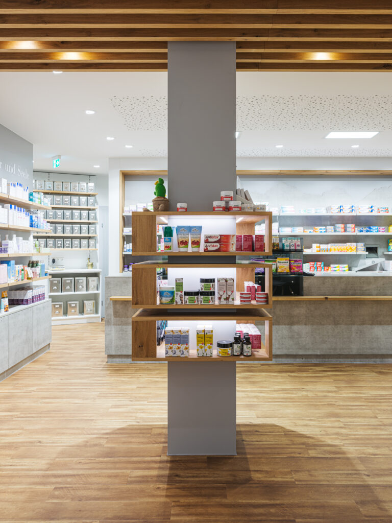 Säule mit Produktregalen mit Holzdesign der Salvenapotheke Söll, Innenarchitektur / Interior Design von Planquelle