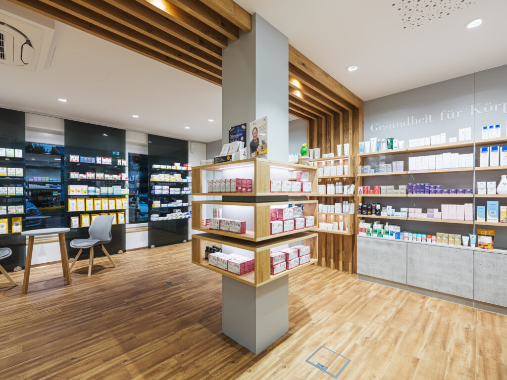 Säule mit Produktregalen mit Holzdesign der Salvenapotheke Söll, Innenarchitektur / Interior Design von Planquelle