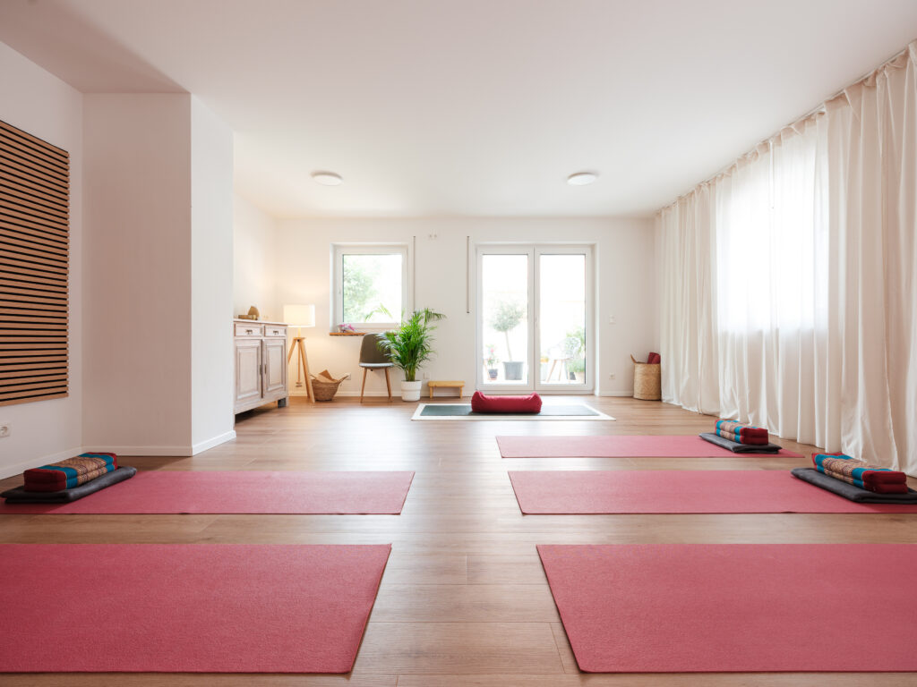 Yogaraum mit Matten, Decken und Kissen mit durch die großen Fenster flutendem Tageslicht im Yogastudio „Das Studio“ in Regensburg