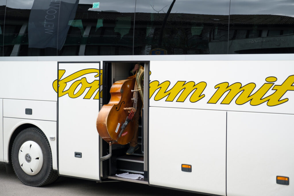 Musiker mit Kontrabass entsteigt einem Reisebus