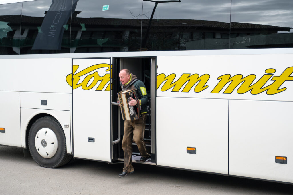 Musiker mit Akkordeon entsteigt einem Reisebus