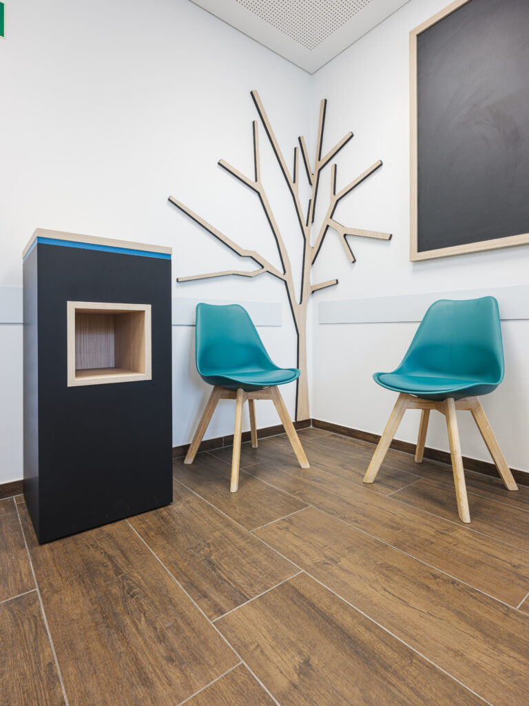 Kindgerechter Wartebereich mit Baumgrafik und Sitzelementen, aufgenommen von Architekturfotograf Alexander Gerner.