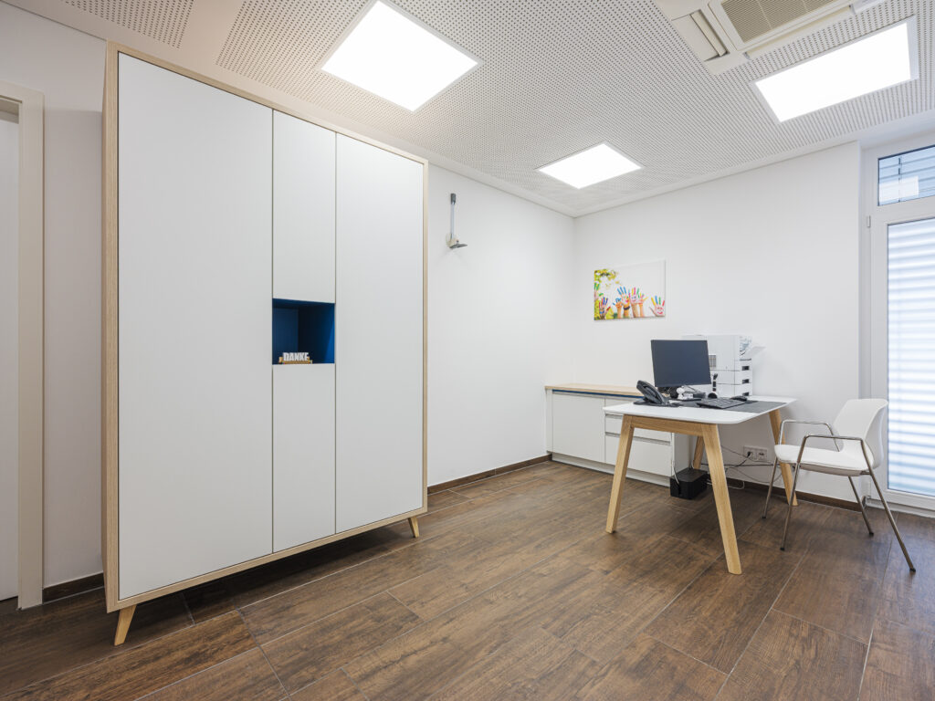 Moderner Praxisraum mit weißem Mobiliar und Holzfußboden, fotografiert von Architekturfotograf Alexander Gerner.