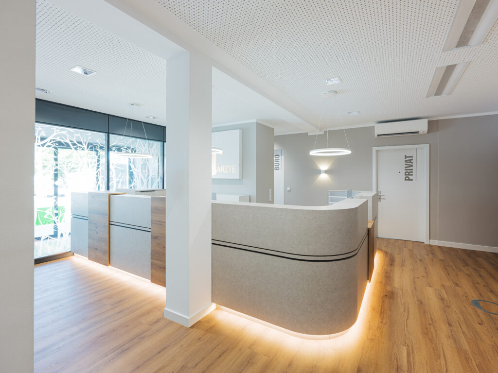Runde Empfangstheke mit weichen Konturen und stimmungsvollem Lichtdesign – fotografiert von Architekturfotograf Alexander Gerner in der Arztpraxis Kögel & Schmiedecke.