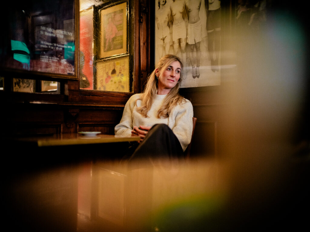 Emotionales Portrait im Orphée Regensburg: Frau im hellen Pullover schaut nach rechts aus dem Bild, im Hintergunrd Wandbilder und Details – Portraitfotografie von Alexander Gerner.