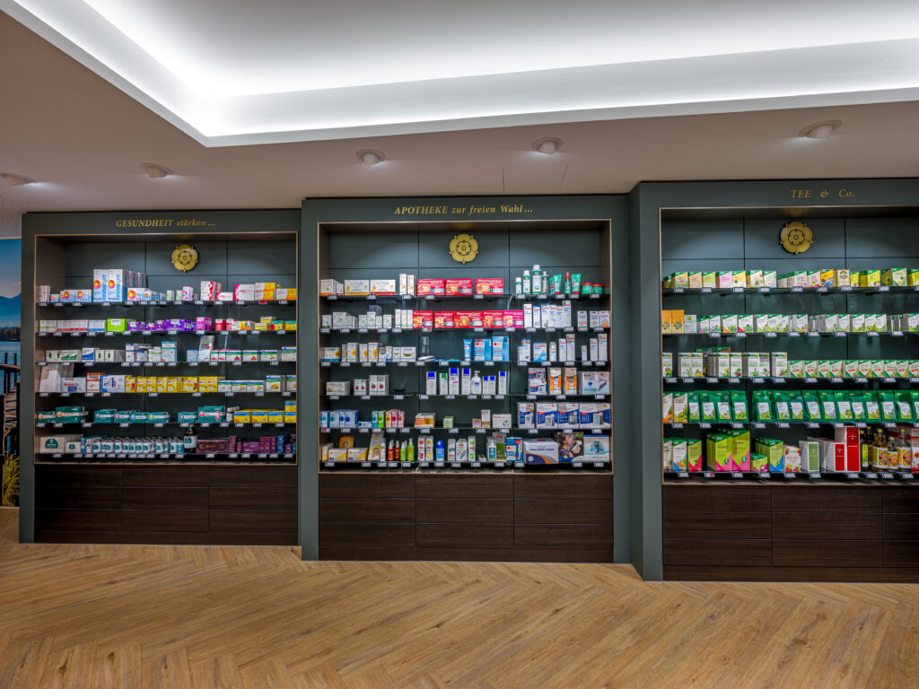 Innenraum mit beleuchteten Produktregalen – Architekturfotograf Alexander Gerner dokumentiert die Rosenapotheke Rosenheim