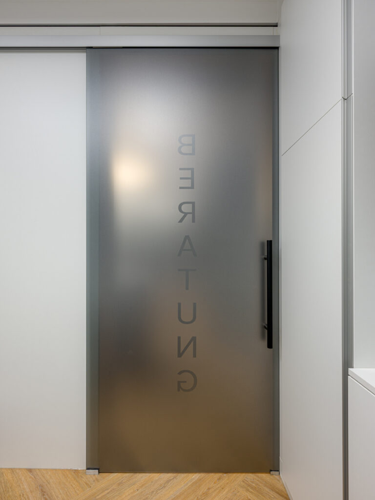 Glastür zwischen Verkaufs- und Beratungsraum der Rosenapotheke bei Rosenheim – Innenarchitekturfotograf Alexander Gerner